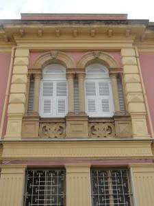 un edificio rosa con dos ventanas blancas. en Casa Tonina, en Carloforte