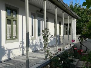 a white house with a porch with flowers on it at Casa din Port in Jurilovca