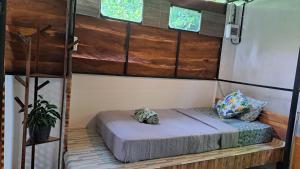 a bed in a room with wooden walls and windows at Big Hug Home in Ko Yao Noi