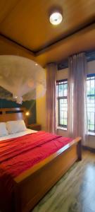 a bedroom with a bed with a red comforter and two windows at Homescapes in Kigali