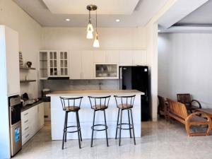a kitchen with a island with three bar stools at Benada Piyungan Yogyakarta by ABM in Yogyakarta