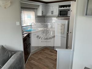 a kitchen with a sink and a refrigerator at E & L Caravan Retreat in Ingoldmells +5 photos