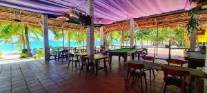 ein Restaurant mit Tischen und Stühlen und dem Meer in der Unterkunft Koh Rong Beach Hostel and Bungalows in Phumĭ Kâoh Rŏng
