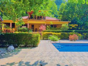 a house with a swimming pool in front of a yard at Casa Mariposa cozy house 5 minutes from the beach in Sámara