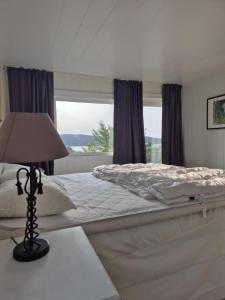 - une chambre avec un grand lit et une lampe sur une table dans l'établissement Neu 55min von Oslo Ferienhaus mit Aussicht Sauna Wassersport, à Berger