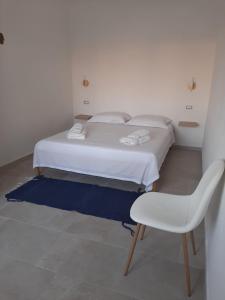 a bedroom with a white bed and a white chair at Villa Lea in Pulsano