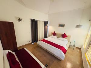 a bedroom with a large white bed with red pillows at Mor Pur - Royal Golf Course Stay in Manesar +11 photos