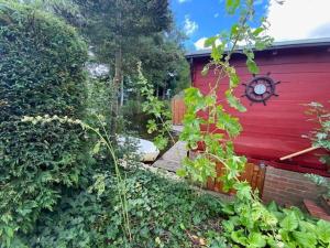 a garden with a red building with a clock on it at Ferienhuus En Söten in Bedekaspel