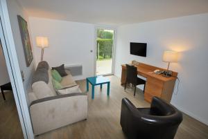 a living room with a couch and a desk at Hotel Le Relais des Champs in Eugénie-les-Bains