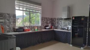 a kitchen with a sink and a refrigerator and a window at Homestay Singgah Tok Dir in Kuala Terengganu