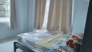 a bed with a comforter on it in a bedroom at Homestay Singgah Tok Dir in Kuala Terengganu +2 photos