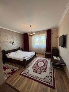 a bedroom with a bed and a table and a television at Hotel Ulpiana, Ethno House in Gracanica