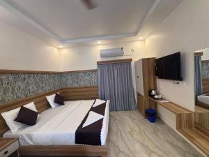 Un dormitorio con una cama y un televisor. en Vainavi Residency, en Tirupati