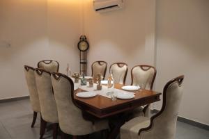 a dining room table with chairs and a clock on the wall at Kaayal Experience - Entire Home in Kozhikode in Kozhikode