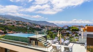 ein Balkon mit Blick auf die Stadt und einen Swimmingpool in der Unterkunft Casa da Ilha in Funchal