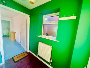 a green room with a window and a radiator at Cozy Comfort Home in Stoke on Trent
