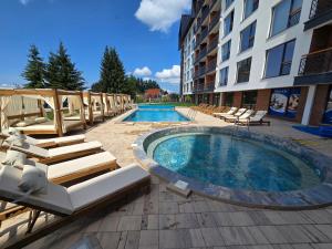 a swimming pool with lounge chairs next to a building at VAB Apartments & SPA, Residence hill, Kopaonik in Kopaonik