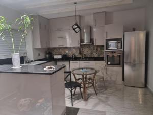 a kitchen with white cabinets and a table with chairs at Résidence Mila in Sukrah