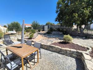 Un patio con mesa y sillas y un muro de piedra. en Maison vendéene bord de mer - env 1 km plage-, en Saint-Vincent-sur-Jard