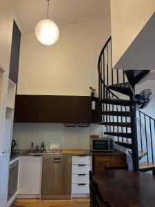 a kitchen with a table and a spiral staircase at Brickworks Heritage Loft in Melbourne