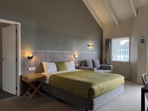 a bedroom with a large bed and a chair at Airport Manor Inn in Auckland