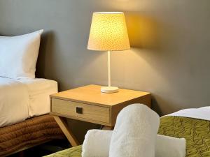 a table with a lamp and a chair in a hotel room at Airport Manor Inn in Auckland