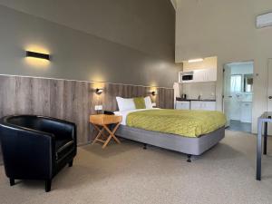 a bedroom with a bed and a black chair at Airport Manor Inn in Auckland +43 photos