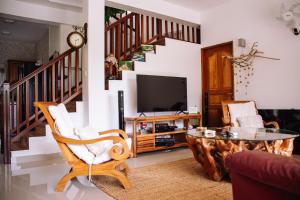 a living room with a tv and a staircase at SOUTH HILL VILLA in Mahe