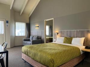 a hotel room with a large bed and a chair at Airport Manor Inn in Auckland