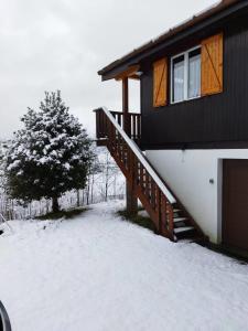 Una casa con un porche cubierto de nieve y un árbol. en Chalet le Petit Coeur, en Xonrupt-Longemer