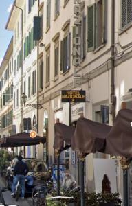 a man riding a bike down a city street with umbrellas at Aramis Deluxe Rooms in Florence