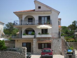 a large house with a balcony and an umbrella at Apartments Zatezalo A4+2 in Omišalj