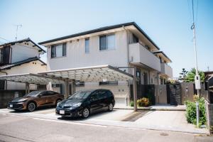 two cars parked in a parking lot in front of a house at Fukuoka Airport WEST in Shime