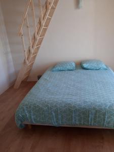 ein Bett mit einer blauen Bettdecke in einem Zimmer mit einer Treppe in der Unterkunft Domaine de la Marandine in Le Vigan