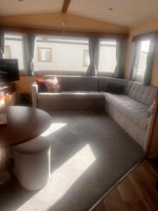 a living room with a couch and a table at Your Happy Place - 8 Berth Caravan 5 minutes from lovely sandy beach in Heacham +1 photo