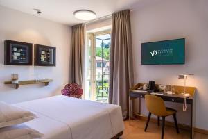 a hotel room with a bed and a desk and a window at Villaggio Narrante - Le Case dei Conti Mirafiore in Serralunga d'Alba
