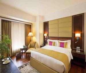 a hotel room with a large bed and a chair at Hotel Hampton International Near Delhi Airport in New Delhi