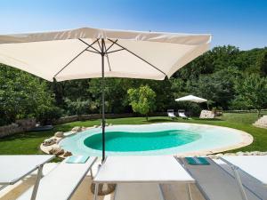 una piscina con sombrilla, mesa y sillas en Villa Molinum, en Palazzolo Acreide