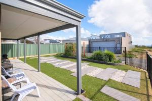a patio with two white chairs on the grass at The Foxes Den- secure yard, WIFI in Geographe