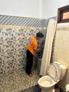 スミニャックにあるJepun BnB Baliのトイレの隣の浴室に立っている女性