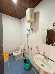 une salle de bain avec un lavabo, des toilettes et un miroir dans l'établissement kedar hill resort, à Sonprayag