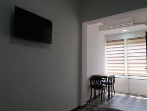 a room with a table with chairs and a television on the wall at Apartmani Krnić in Tuzi