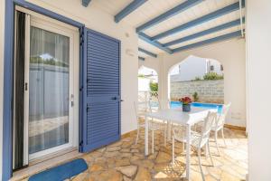 a patio with a white table and chairs and a blue door at Appartamento Playa Lapillo in Nardò
