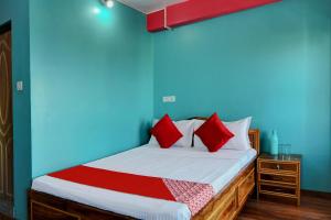 a bed with red pillows in a blue room at Hotel O Chewang Homestay in Darjeeling