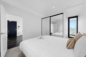a white bedroom with a large bed and a large mirror at Stylish 2BR with Story Bridge & Fireworks Views in Brisbane