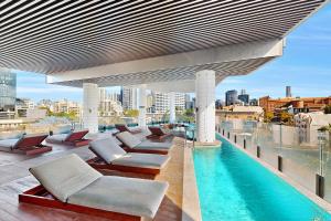 a rooftop patio with chairs and a pool on a building at Stylish 2BR with Story Bridge & Fireworks Views in Brisbane +9 photos