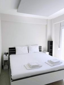 a white bedroom with a large white bed with white pillows at Anesis in Néa Péramos
