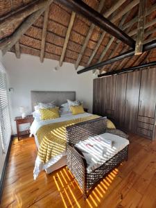 a bedroom with a bed and a chair in a room at The Whispering Milkwood Cottage in Gqeberha
