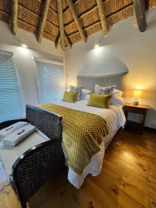 a bedroom with a large bed and a table at The Whispering Milkwood Cottage in Gqeberha