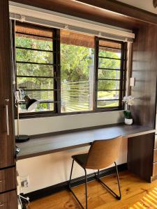 a desk in a room with a window with a chair at The Whispering Milkwood Cottage in Gqeberha +12 photos